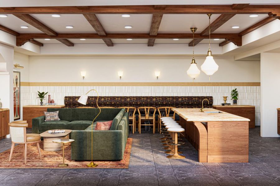 Modern kitchen and living area with wood accents, green sofa, island seating, and exposed ceiling beams.